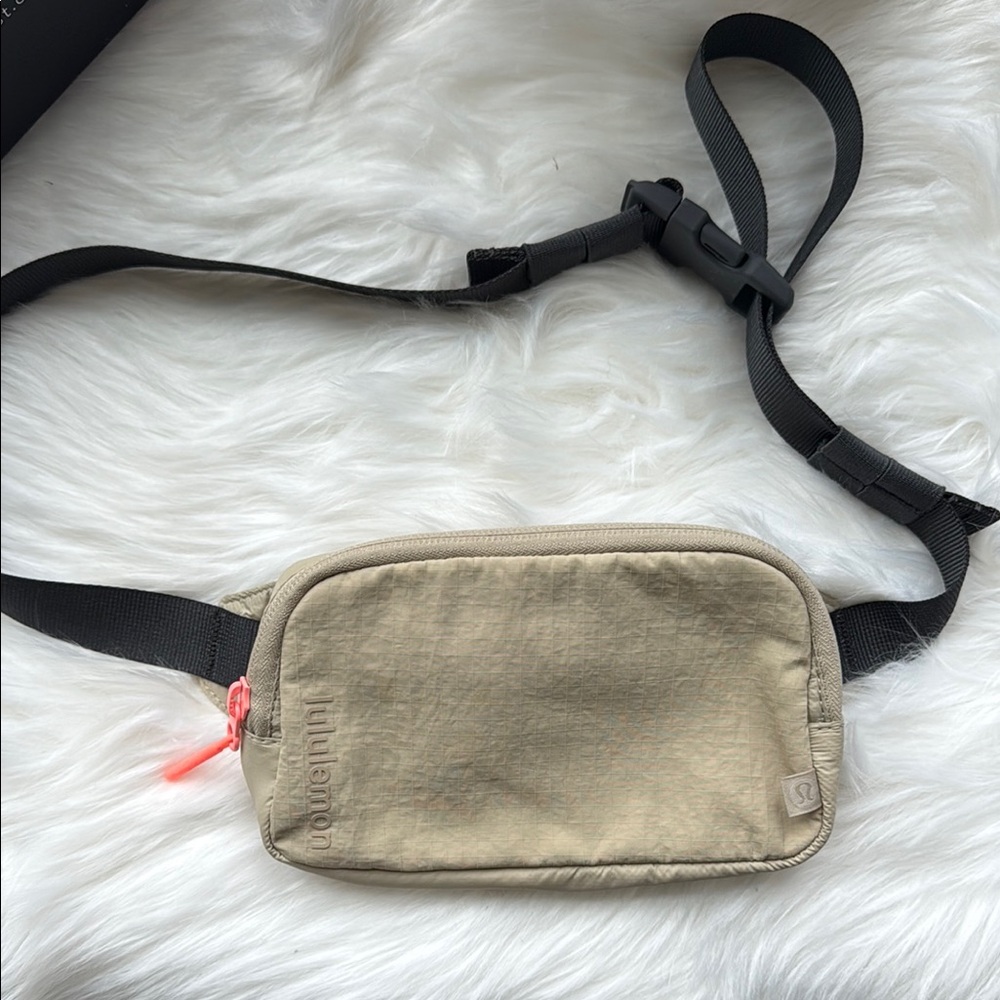 lululemon athletica beige waist pack with black strap and pink zipper pull
